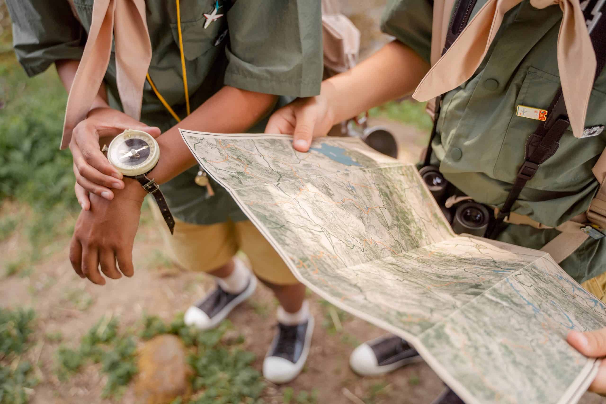 Kinder beim Wandern mit Karte und Kompass im Wald.